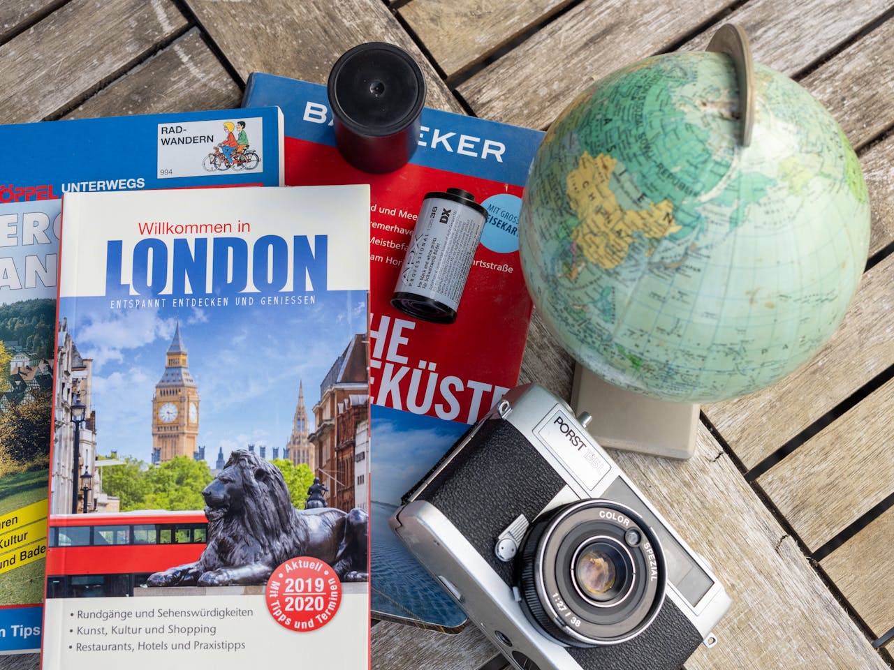 services-02 Flat lay featuring London travel guide, vintage camera, and globe, ideal for travel theme.