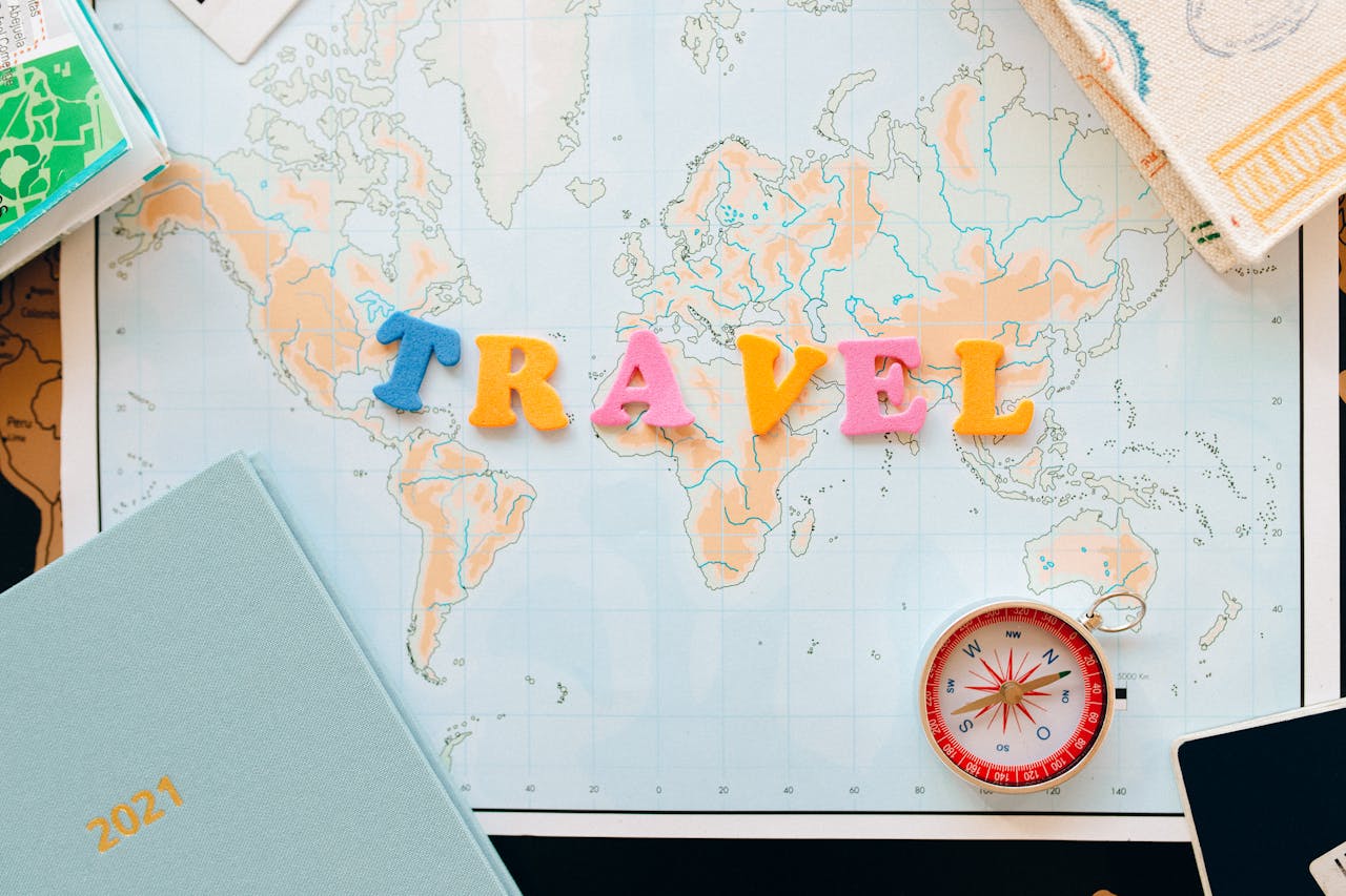 services-04 Flat lay of a map with colorful letters "TRAVEL" and a compass for planning adventures.